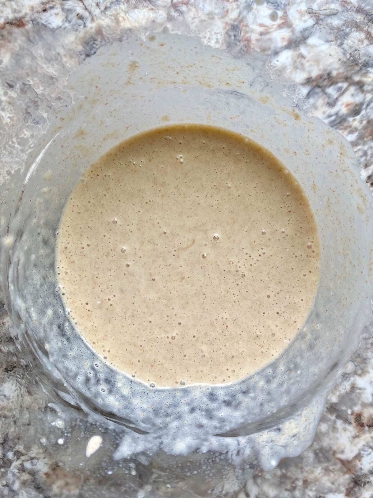 Mashed banana, sourdough discard, and other wet ingredients in a glass bowl.