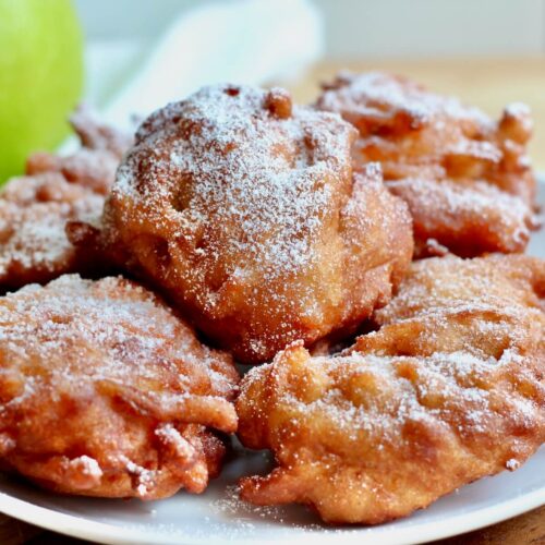 A plate of sourdough apple fritters sprinkled with powdered sugar.