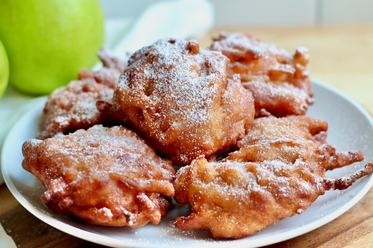 A plate of sourdough apple fritters sprinkled with powdered sugar.