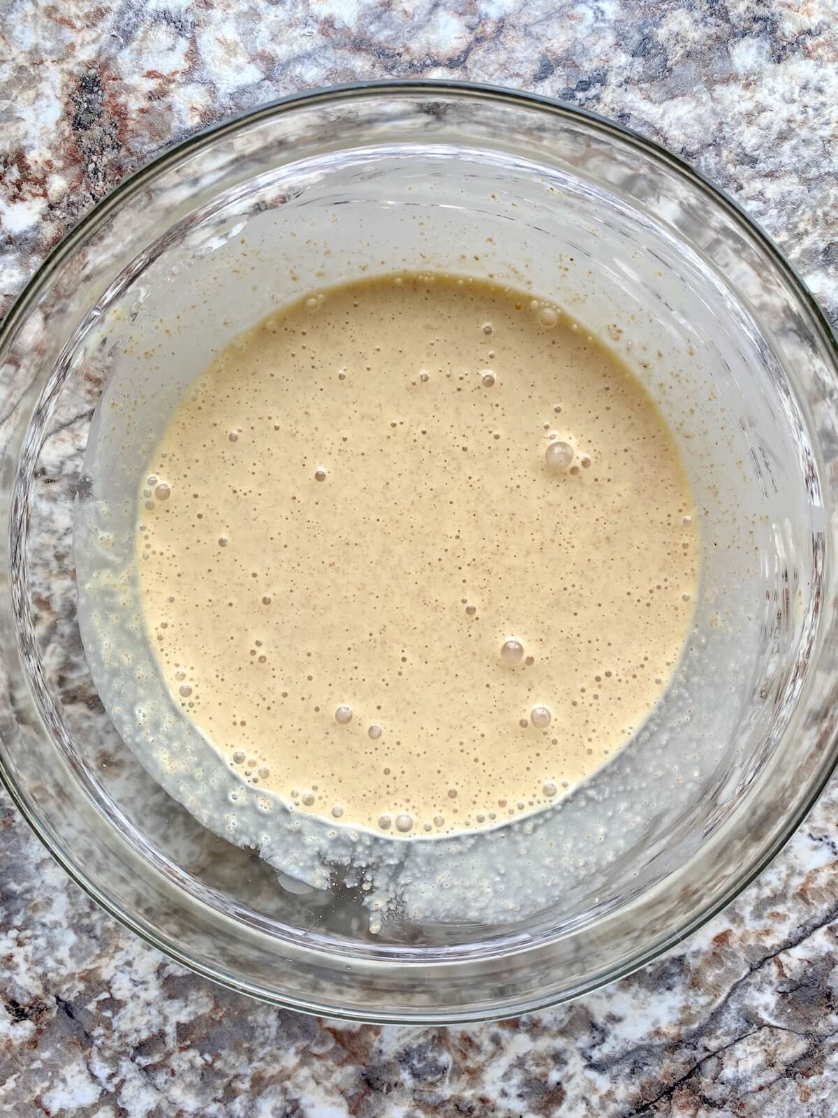 Sourdough discard, cream, and other ingredients mixed together in a glass bowl.