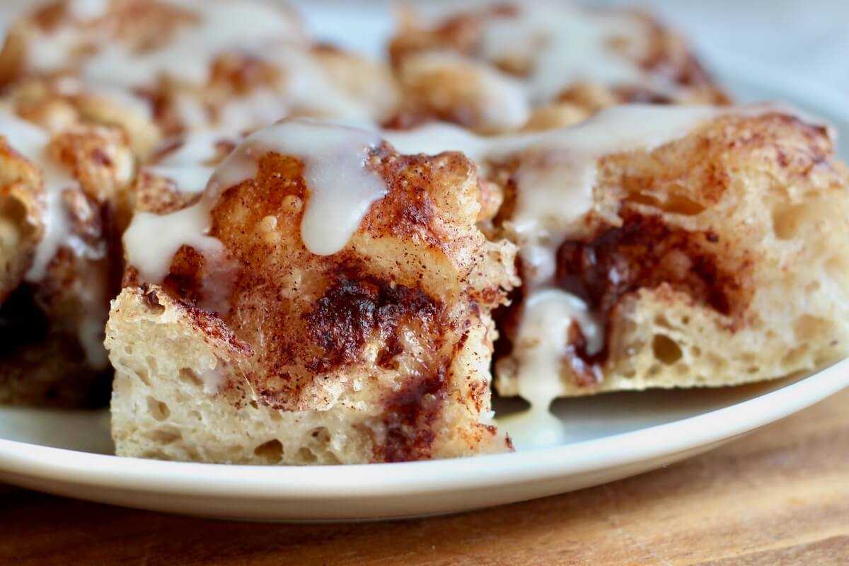Sourdough cinnamon roll focaccia with icing on a small plate.