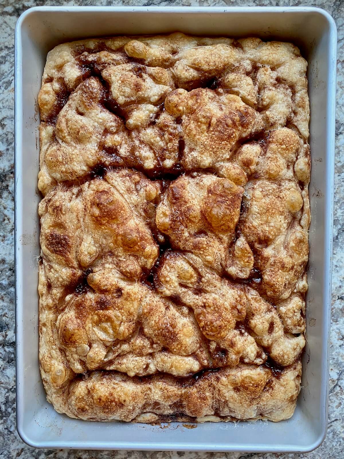 Sourdough discard cinnamon roll focaccia in an aluminum baking pan before baking.