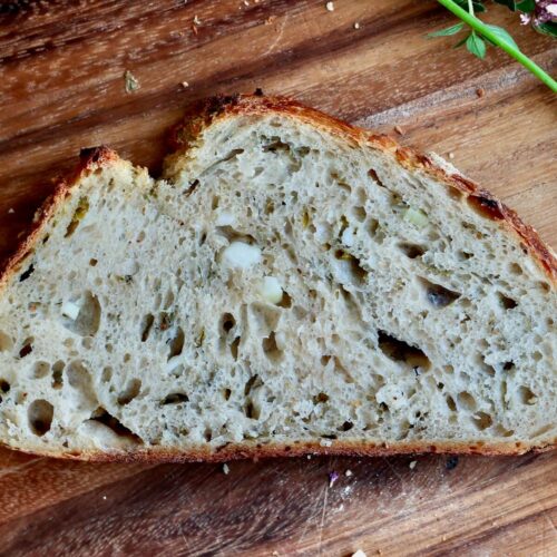 A slice of garlic sourdough bread on a wooden cutting board.
