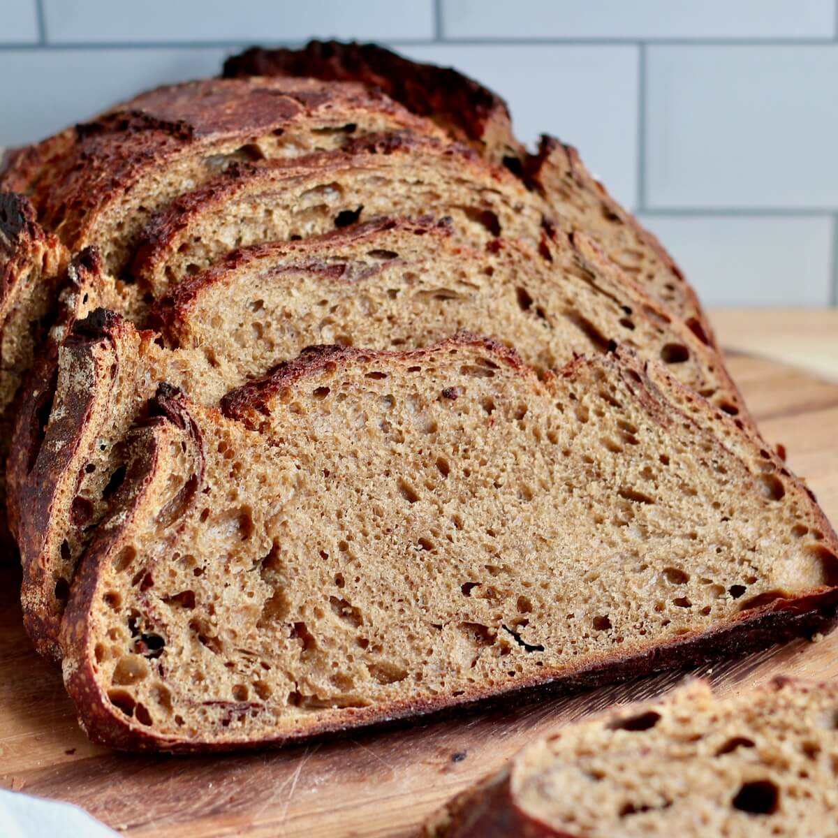 A loaf of gingerbread sourdough bread cut into slices on a cutting board.