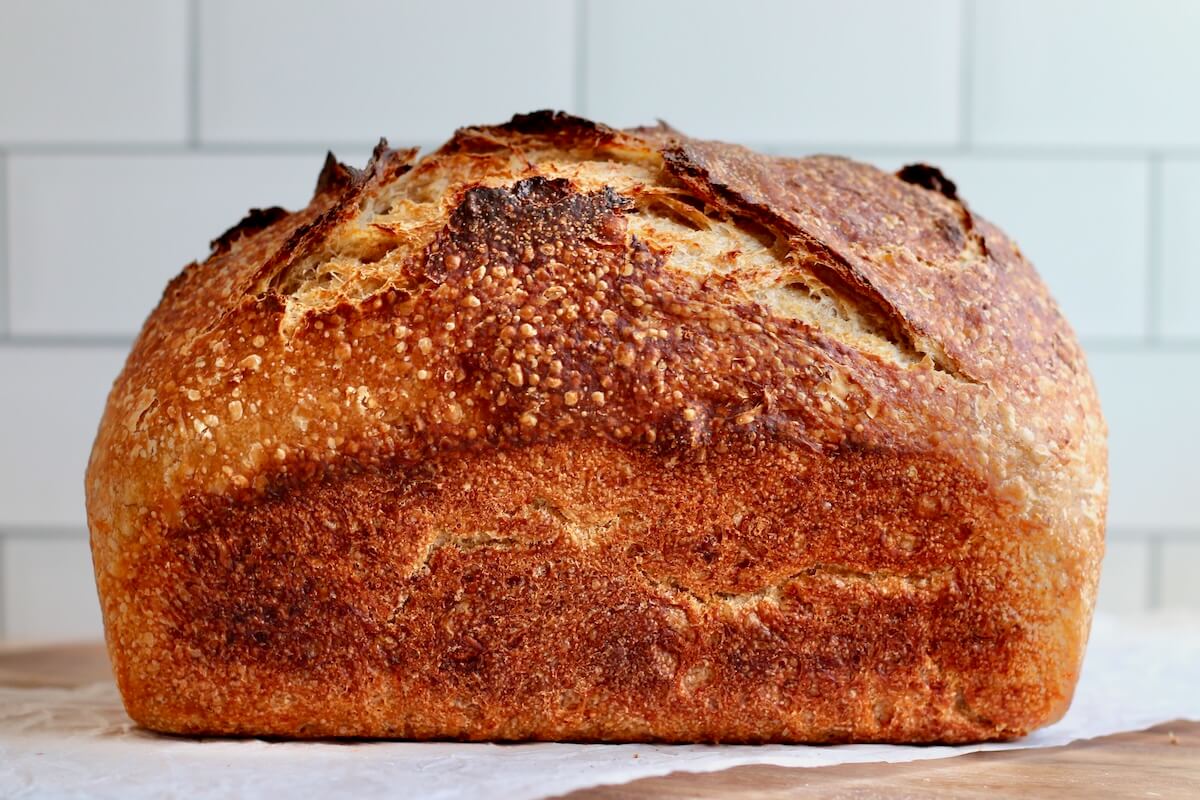 A whole loaf of uncut oatmeal sourdough bread on a counter.