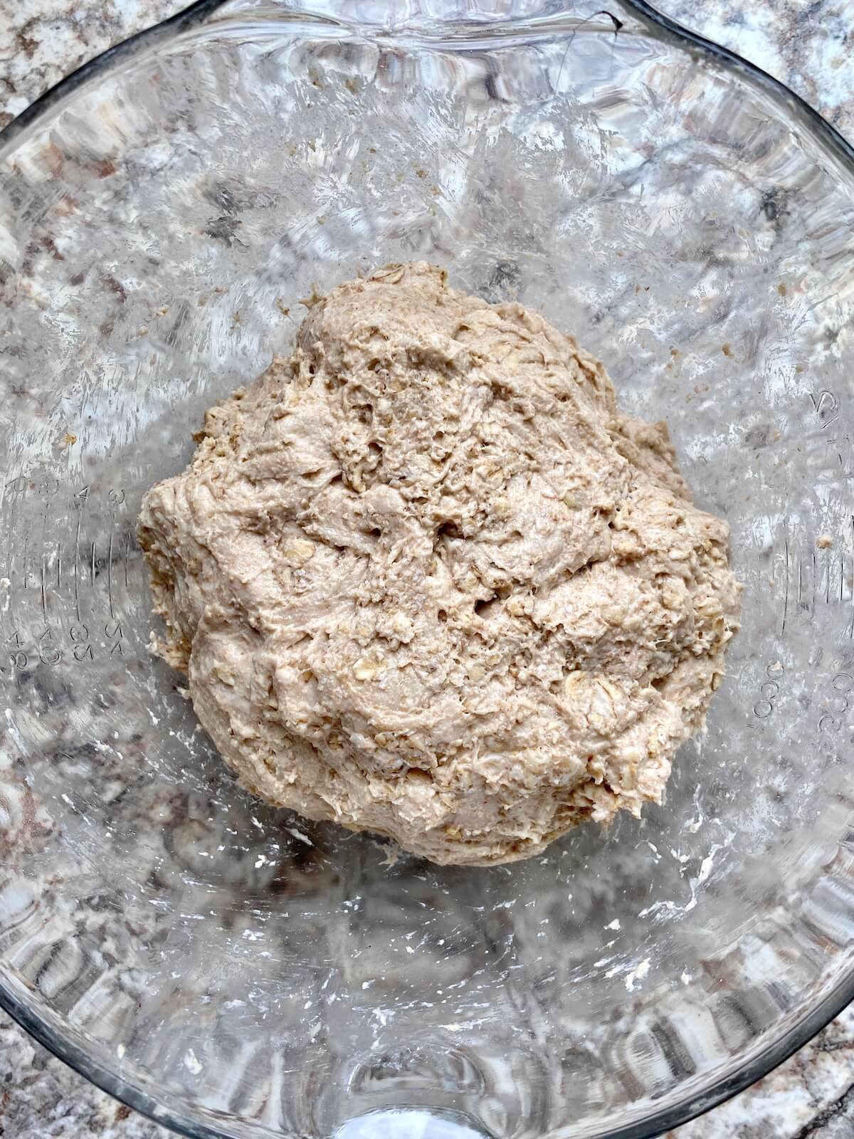 Sourdough oatmeal bread dough in a glass bowl.