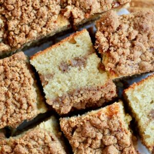 Pieces of sourdough coffee cake on a parchment paper. Some of the pieces are flipped on their side to show the cinnamon sugar layers.