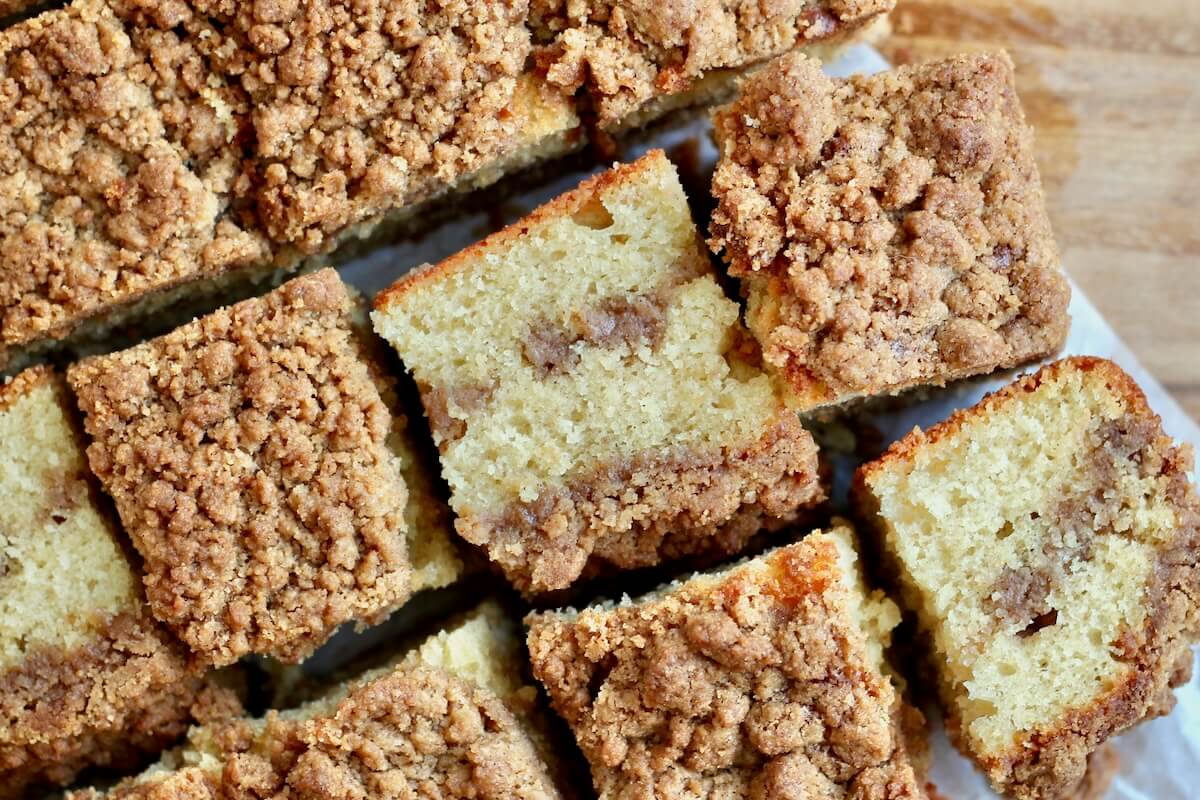 Pieces of sourdough coffee cake on a parchment paper. Some of the pieces are flipped on their side to show the cinnamon sugar layers.