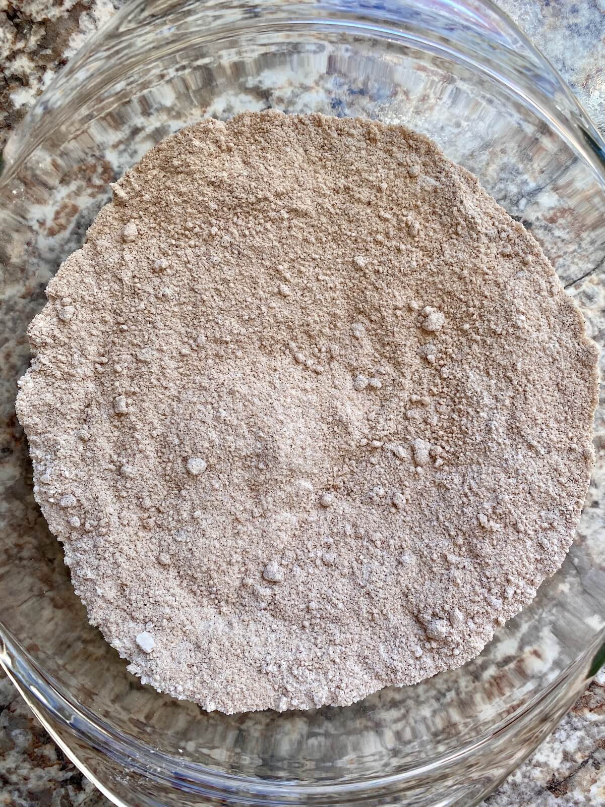 Flour, brown sugar, cinnamon, and salt mixed together in a glass bowl to make the base for the crumble topping and filling.