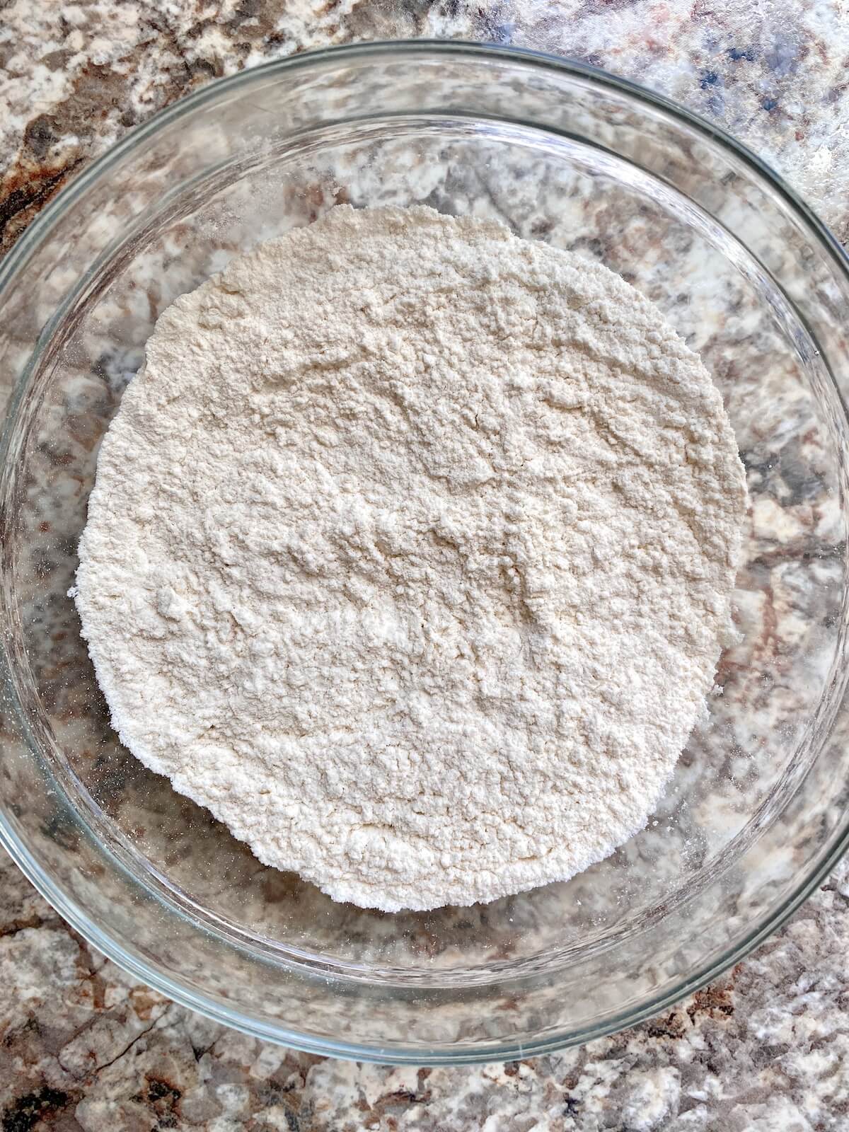 The dry ingredients for the cake mixed together in a glass bowl.