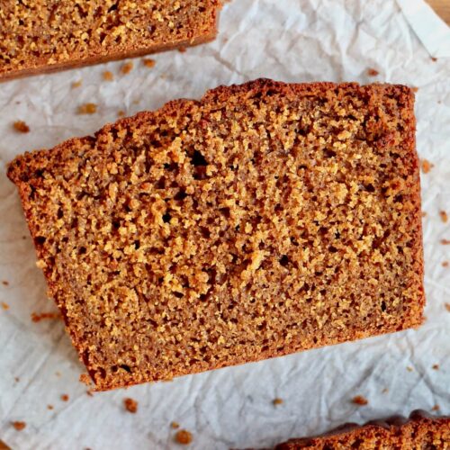 A slice of sourdough gingerbread loaf cake on a piece of parchment paper.