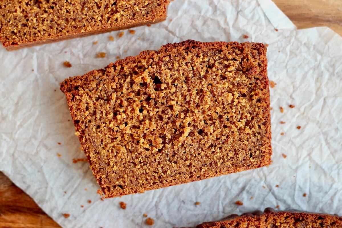 A slice of sourdough gingerbread loaf cake on a piece of parchment paper.
