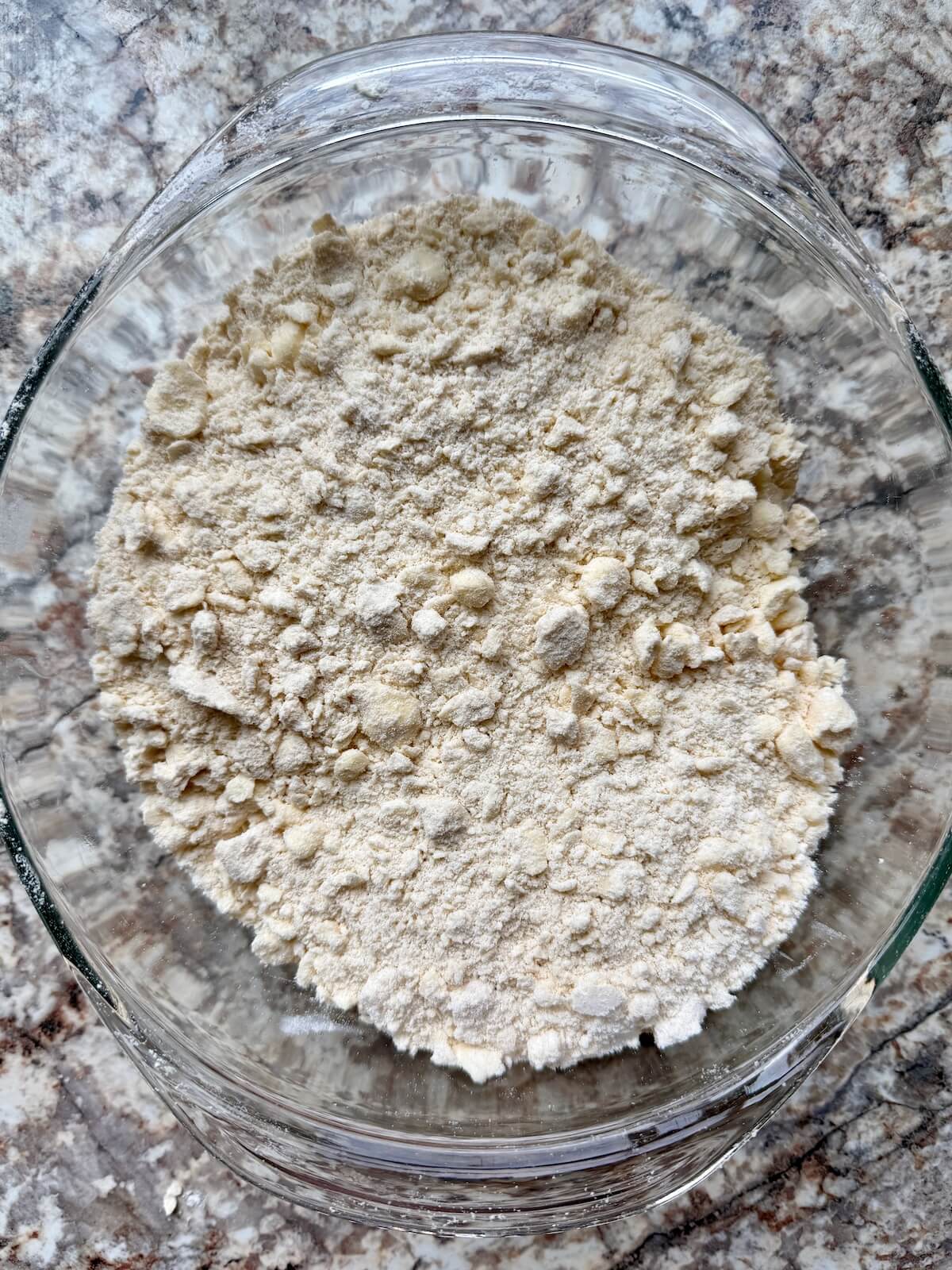 A bowl filled with a mixture of butter and flour to make sourdough discard pie dough.