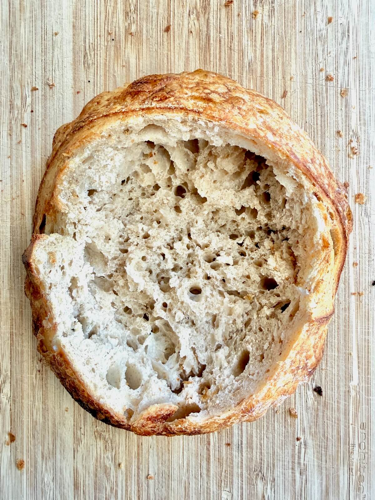 A hollowed out sourdough bread bowl on a cutting board.