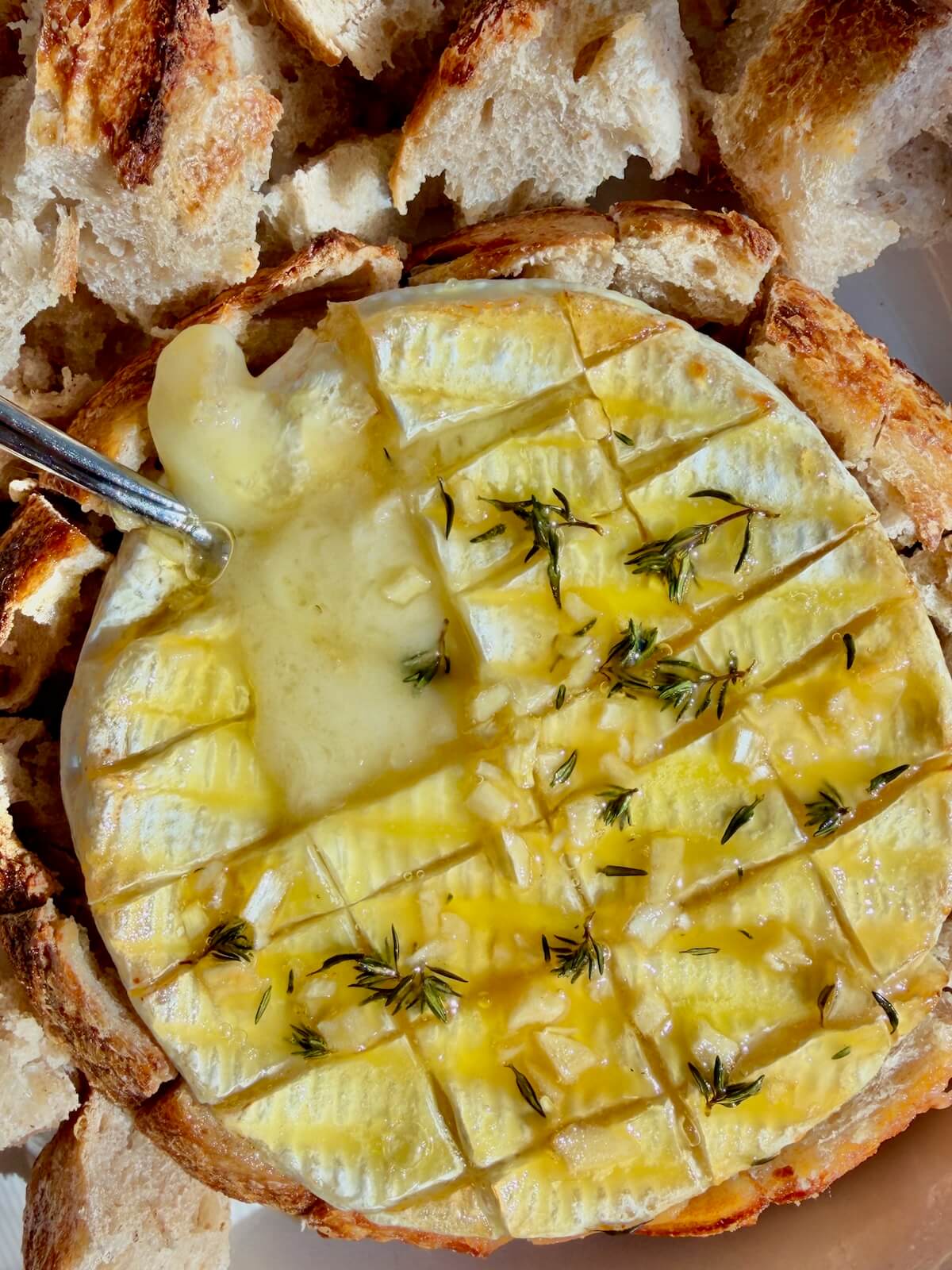 Baked brie in sourdough with a spoon sticking out of the cheese.