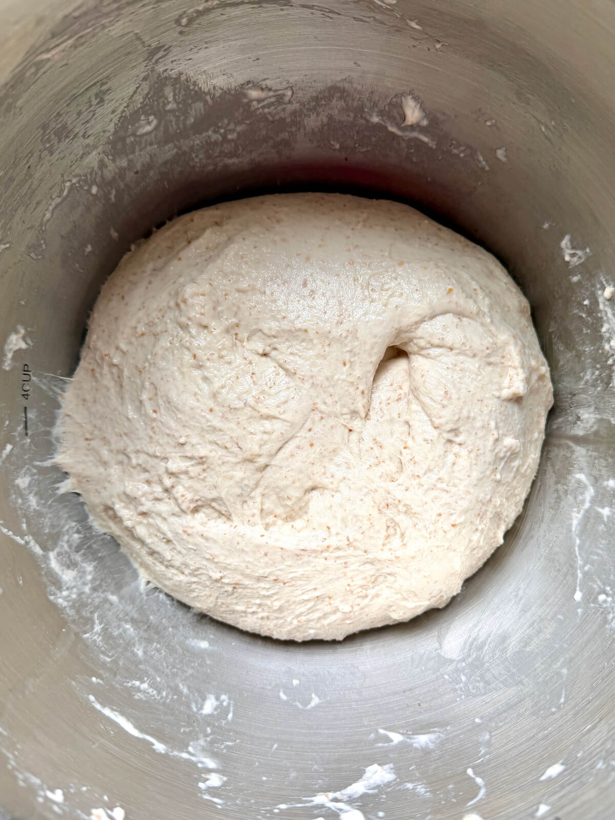 Sourdough focaccia dough in a stainless steel bowl after being stretched and folded.