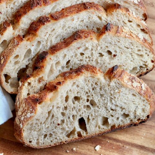 Slices of honey oat sourdough bread on a cutting board.