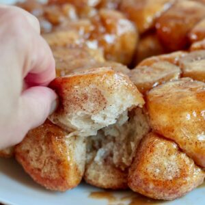 A hand pulling a piece of sourdough monkey bread off the whole loaf.