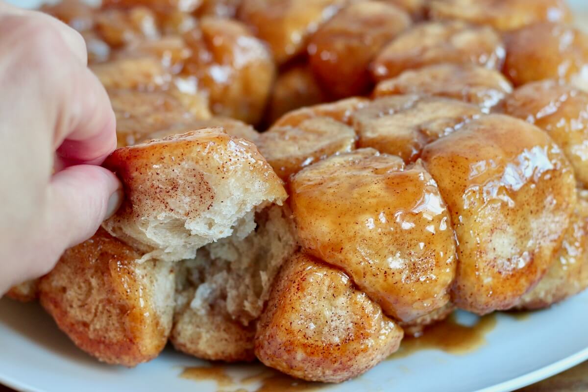 A hand pulling a piece of sourdough monkey bread off the whole loaf.