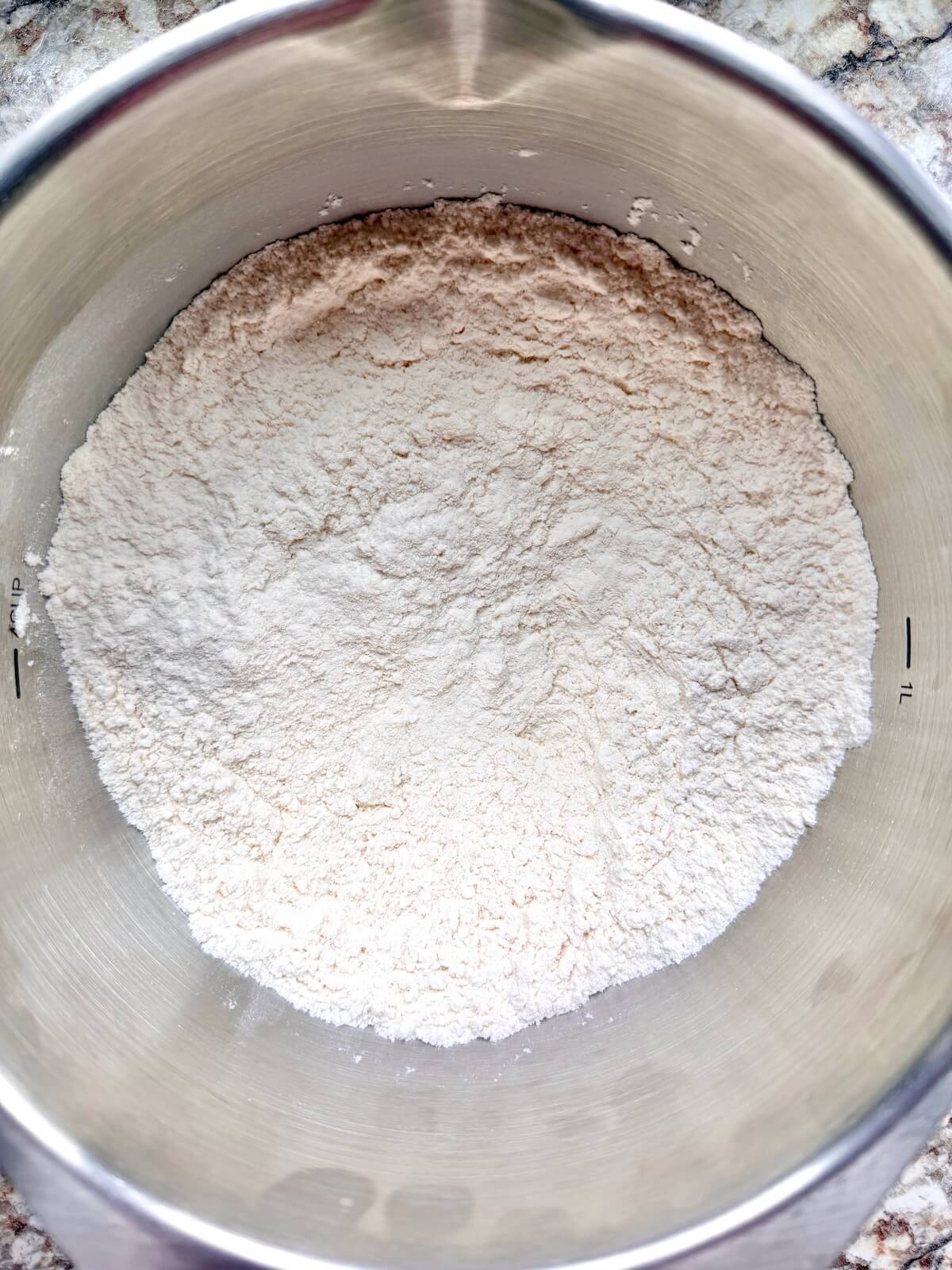 All-purpose flour and other dry ingredients in a stainless steel mixing bowl.