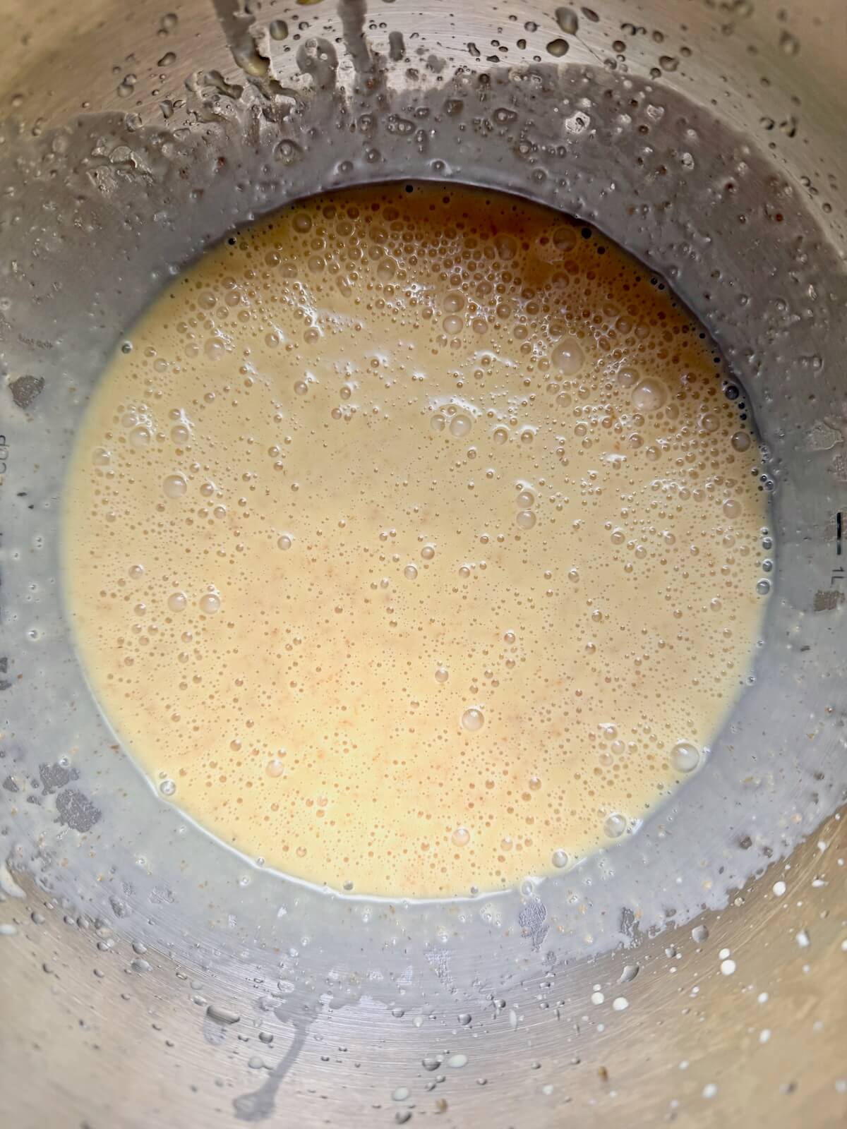 Sourdough discard, milk, eggs, and other wet ingredients in a stainless steel mixing bowl.