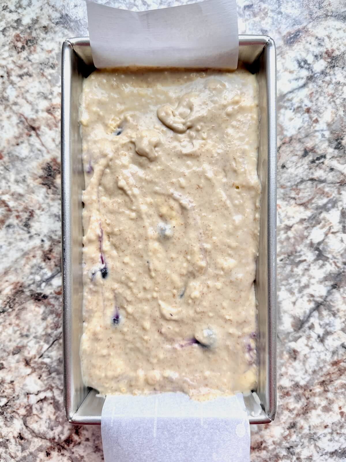 Sourdough blueberry muffin bread batter in a parchment-lined loaf pan.