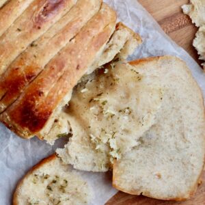 A loaf of sourdough pull apart garlic bread with a few pieces pulled apart.