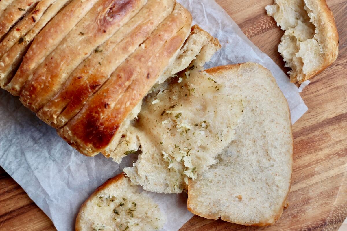 A loaf of sourdough pull apart garlic bread with a few pieces pulled apart.