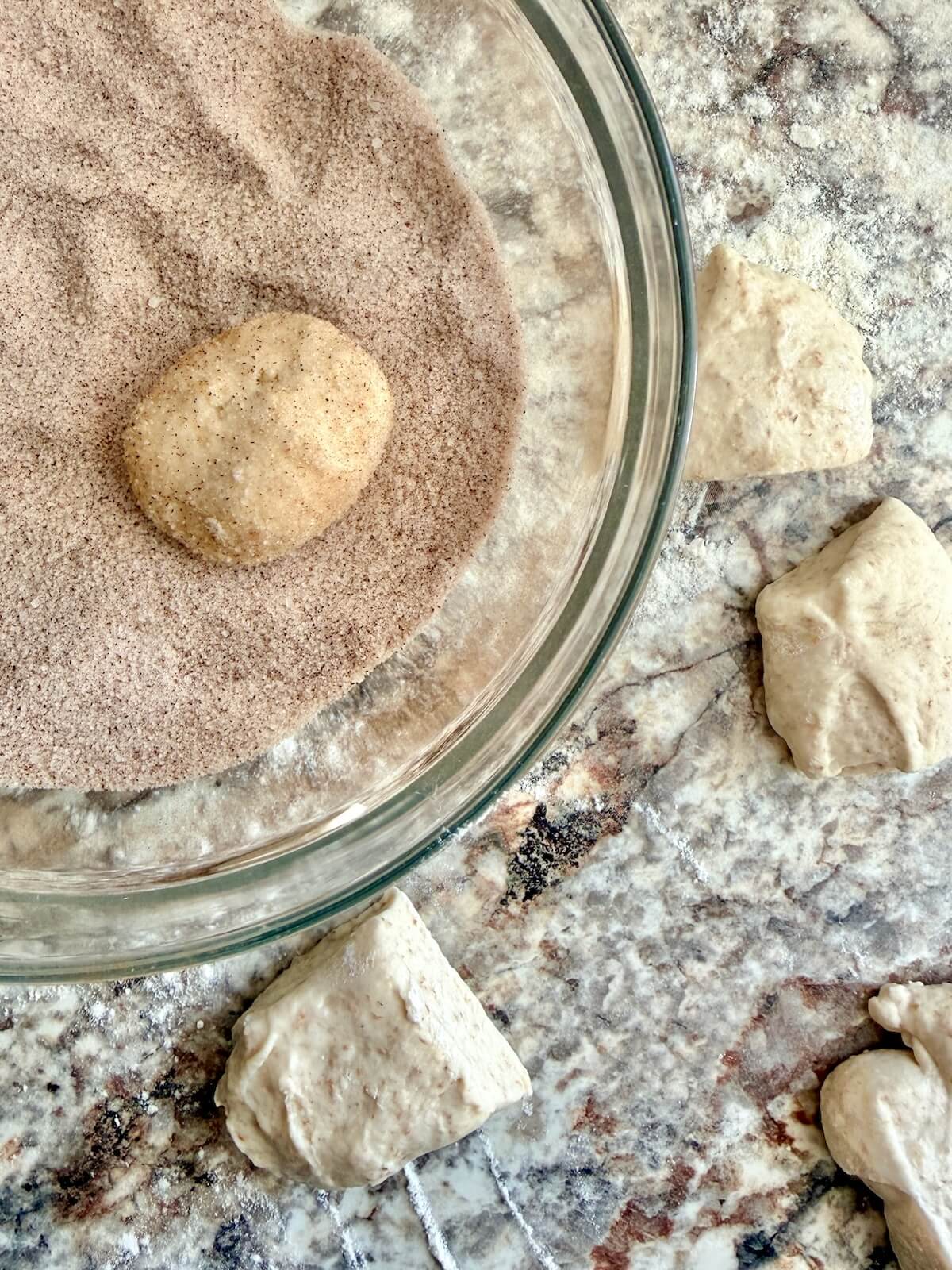 Pieces of dough being rolled in cinnamon sugar.