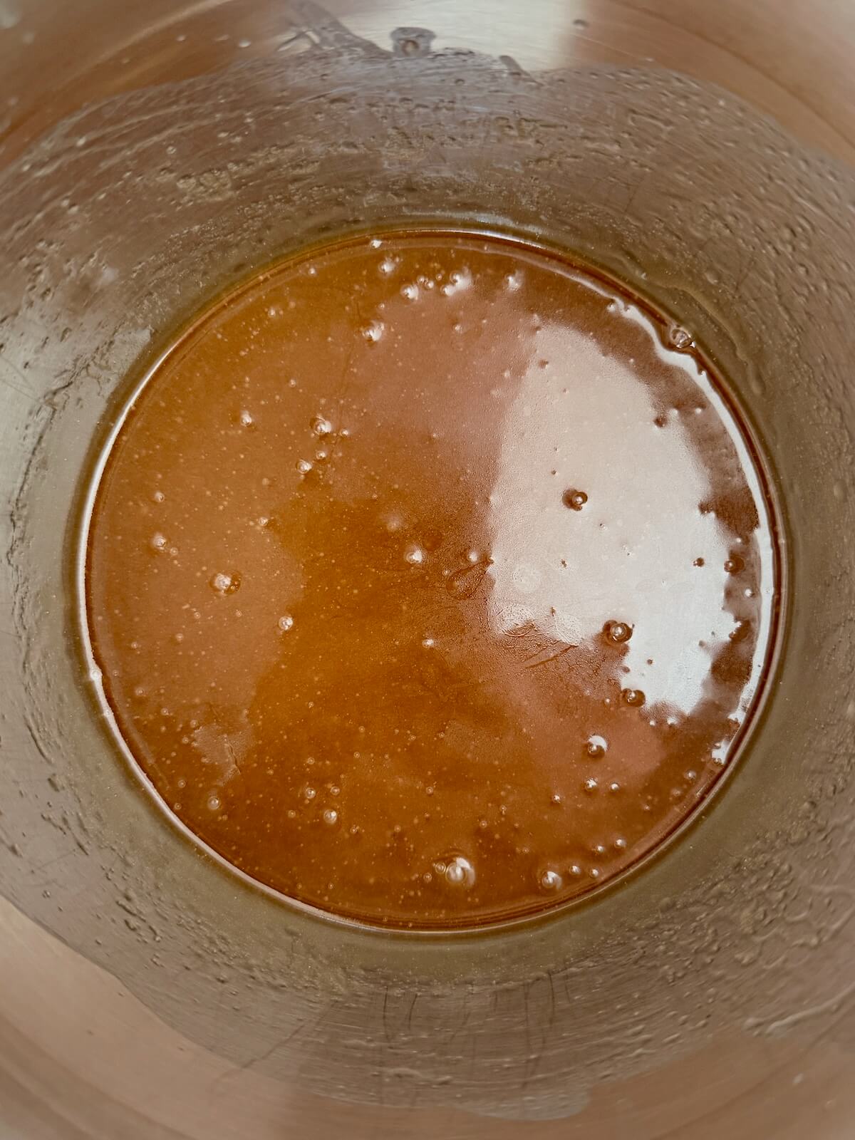 A mixture of butter and brown sugar in a stainless steel saucepan.