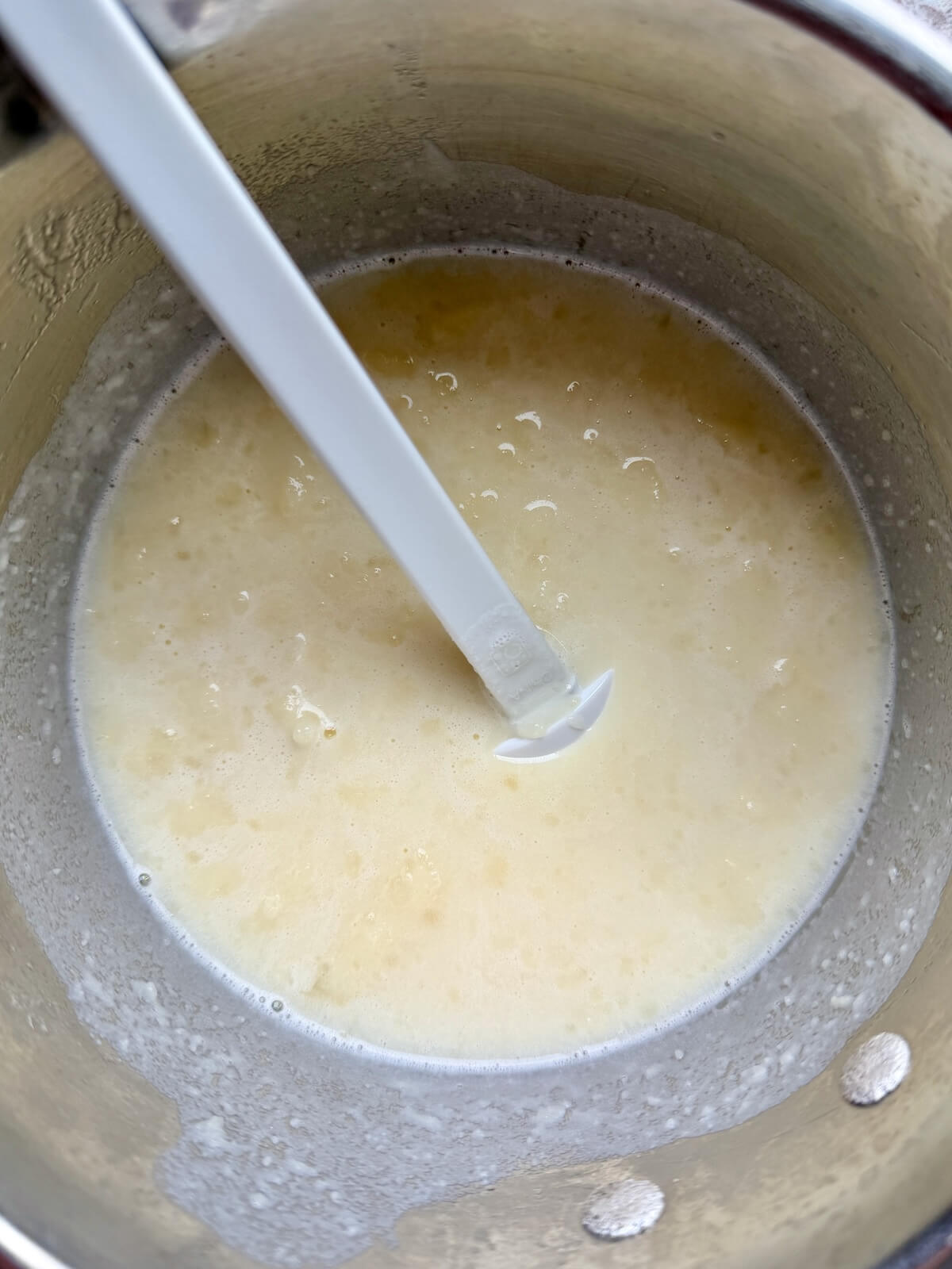 Mashed potatoes mixed with milk, butter, salt, and sugar in a stainless steel pot.