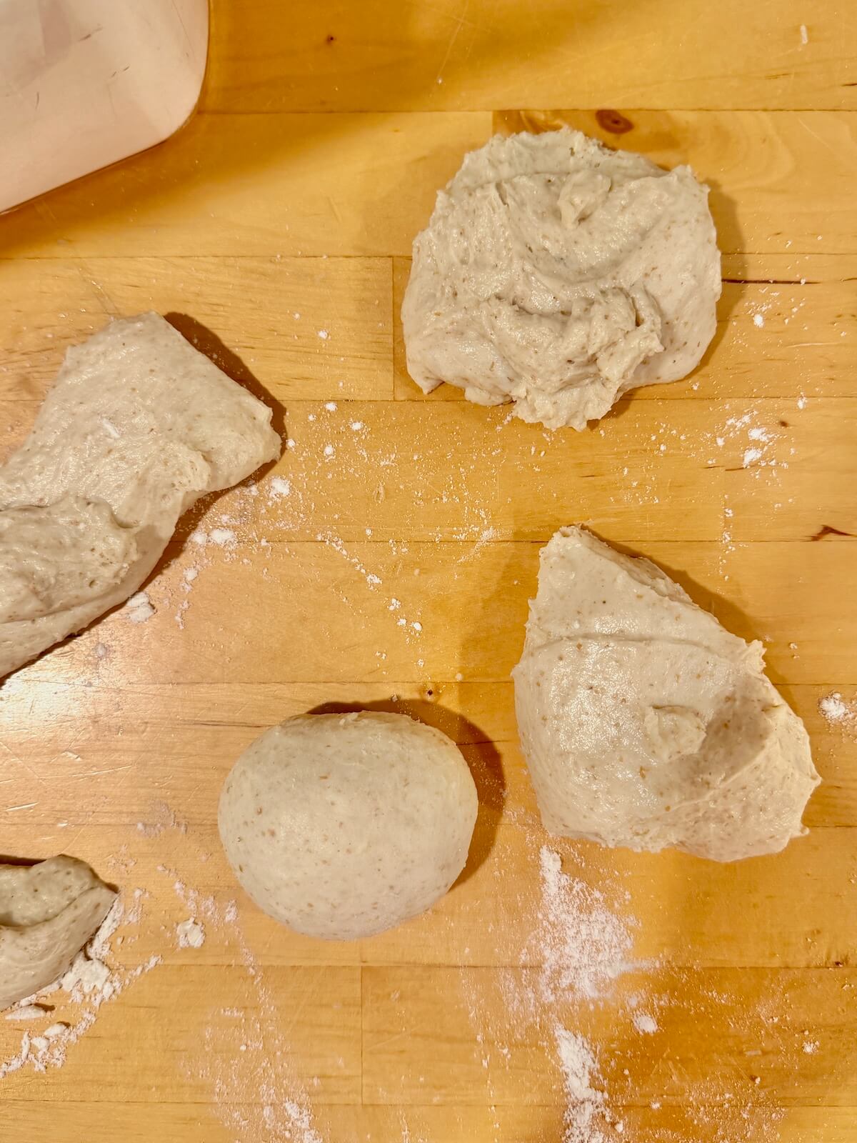 Cut pieces of sourdough potato roll dough on a counter.