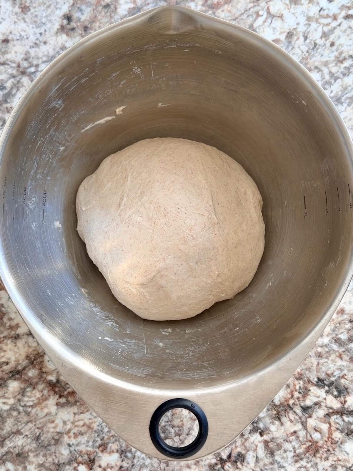 A stretched and folded sourdough bread dough in a stainless steel bowl.