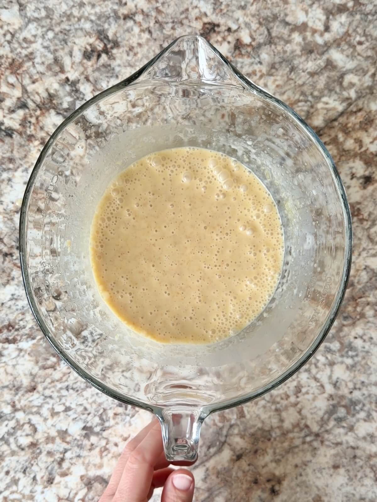Sourdough discard, butter, milk, eggs, and other wet ingredients in a glass mixing bowl.
