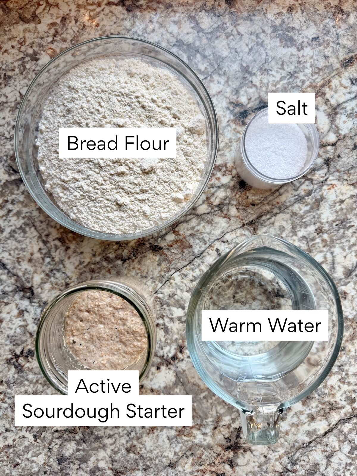 The ingredients to make same day sourdough bread. Each ingredient is labeled with text. They include bread flour, active sourdough starter, warm water, and salt.