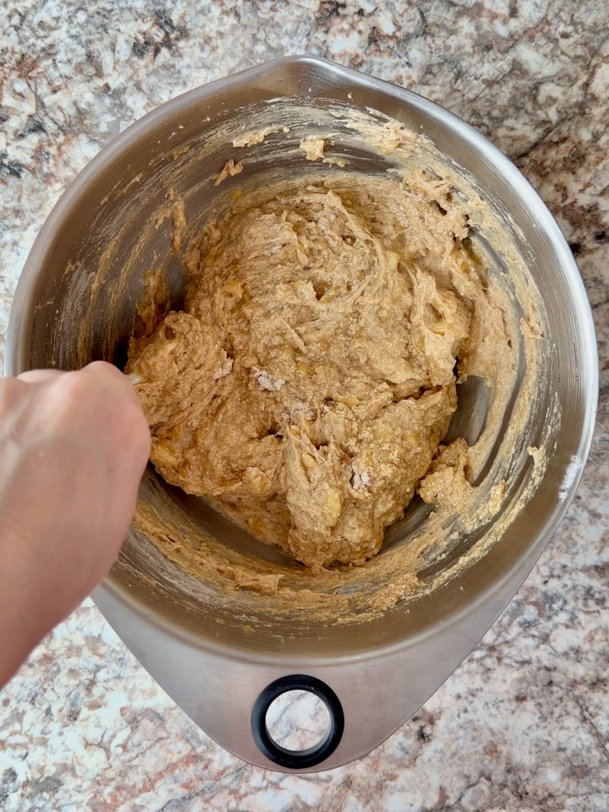 Sourdough banana bread batter being folded together in a bowl.