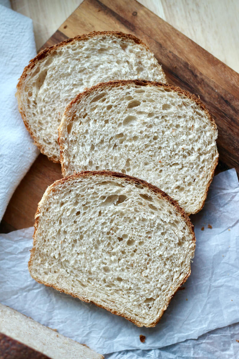 Three slices of sourdough sandwich bread on a cutting board.