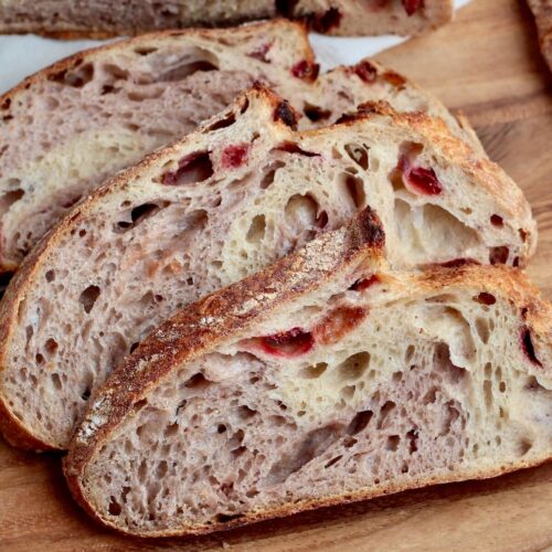 Three slices of strawberry sourdough bread on a wooden cutting board.