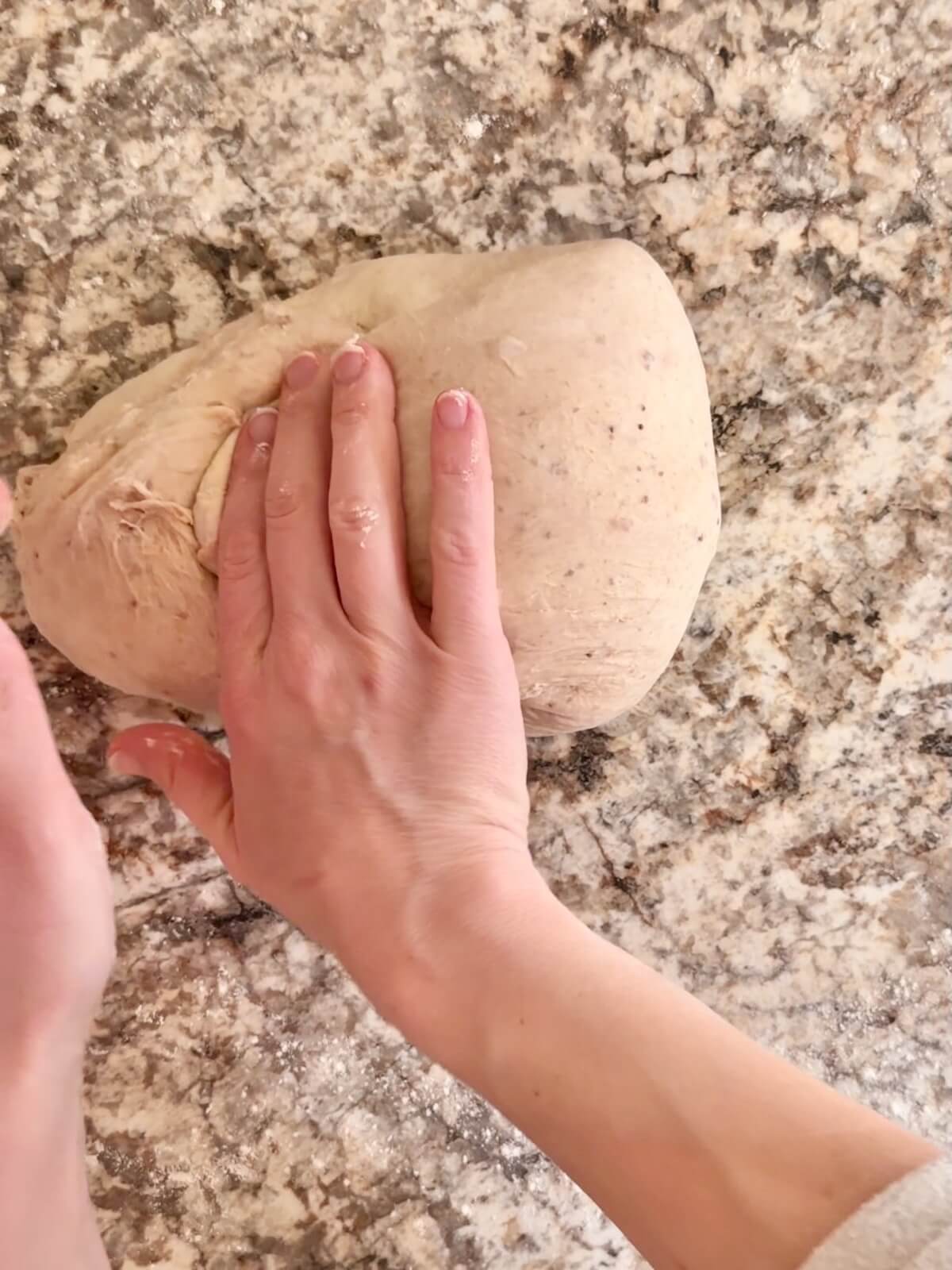 Strawberry sourdough bread dough being shaped on a floured countertop.