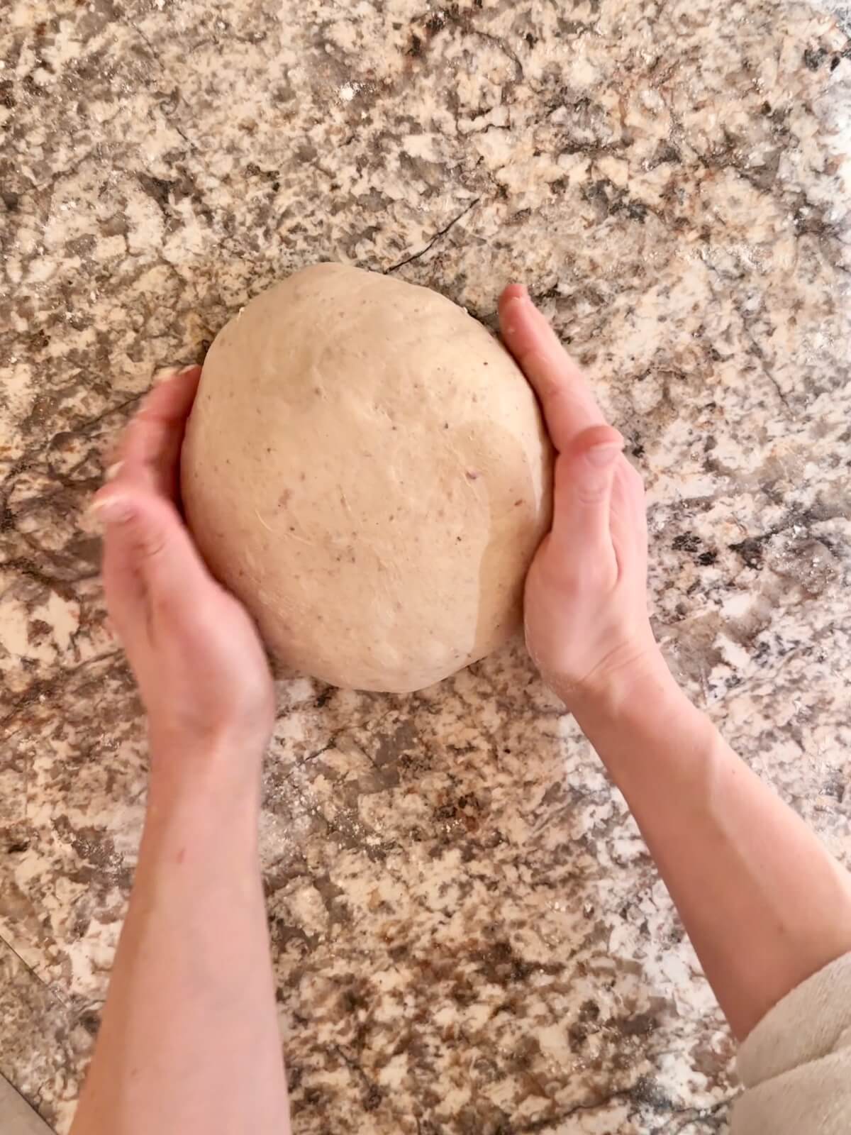 Strawberry sourdough bread dough being shaped on a floured countertop.