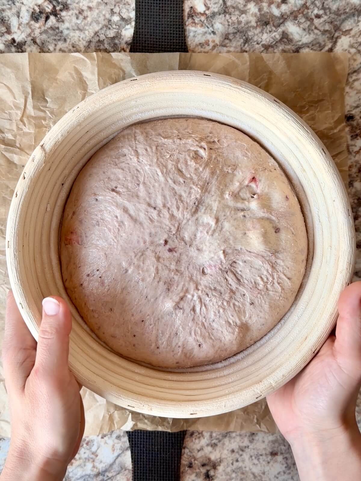 Strawberry sourdough bread dough in a round proofing basket after proofing in the refrigerator overnight.