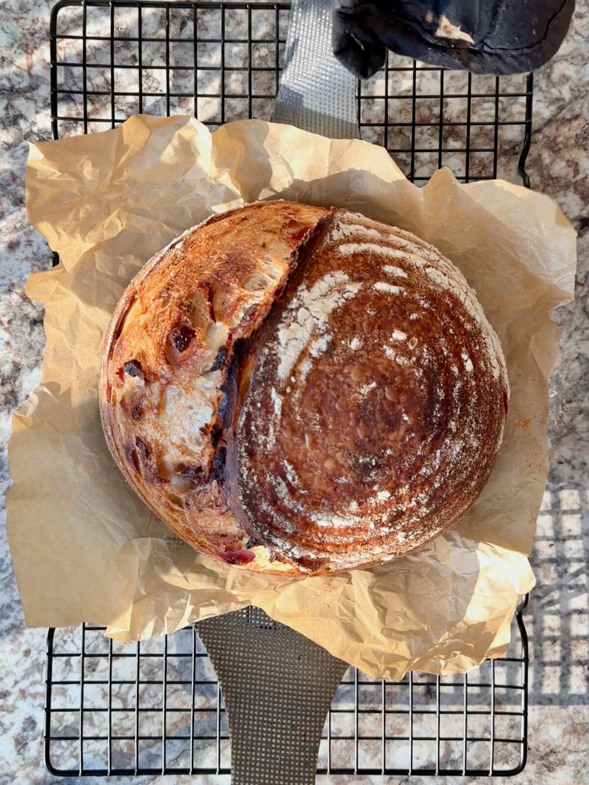 A baked loaf of freeze-dried strawberry sourdough bread on a wire cooling rack.