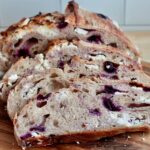 Slices of blueberry cream cheese sourdough bread on a wooden cutting board.