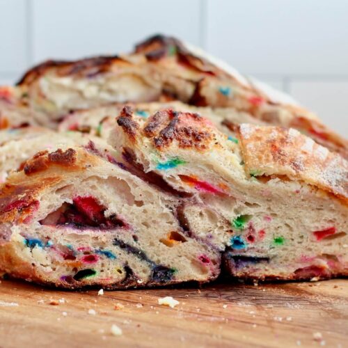 Slices of funfetti sourdough bread on a wooden cutting board.