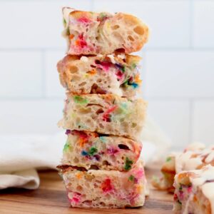 A stack of 5 pieces of funfetti sourdough focaccia bread. There are two more pieces off to the side of the stack.