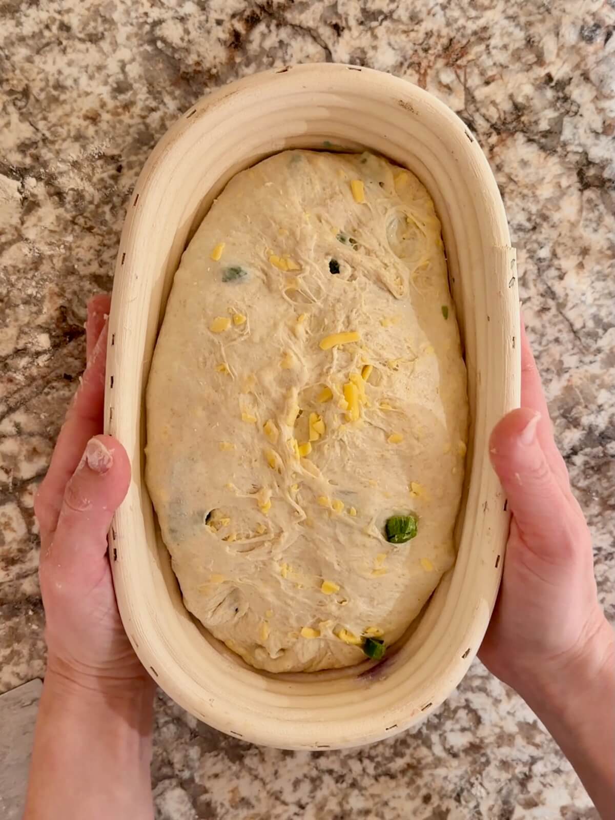 JalapeƱo cheddar sourdough bread dough in an oval proofing basket before cold proofing overnight.