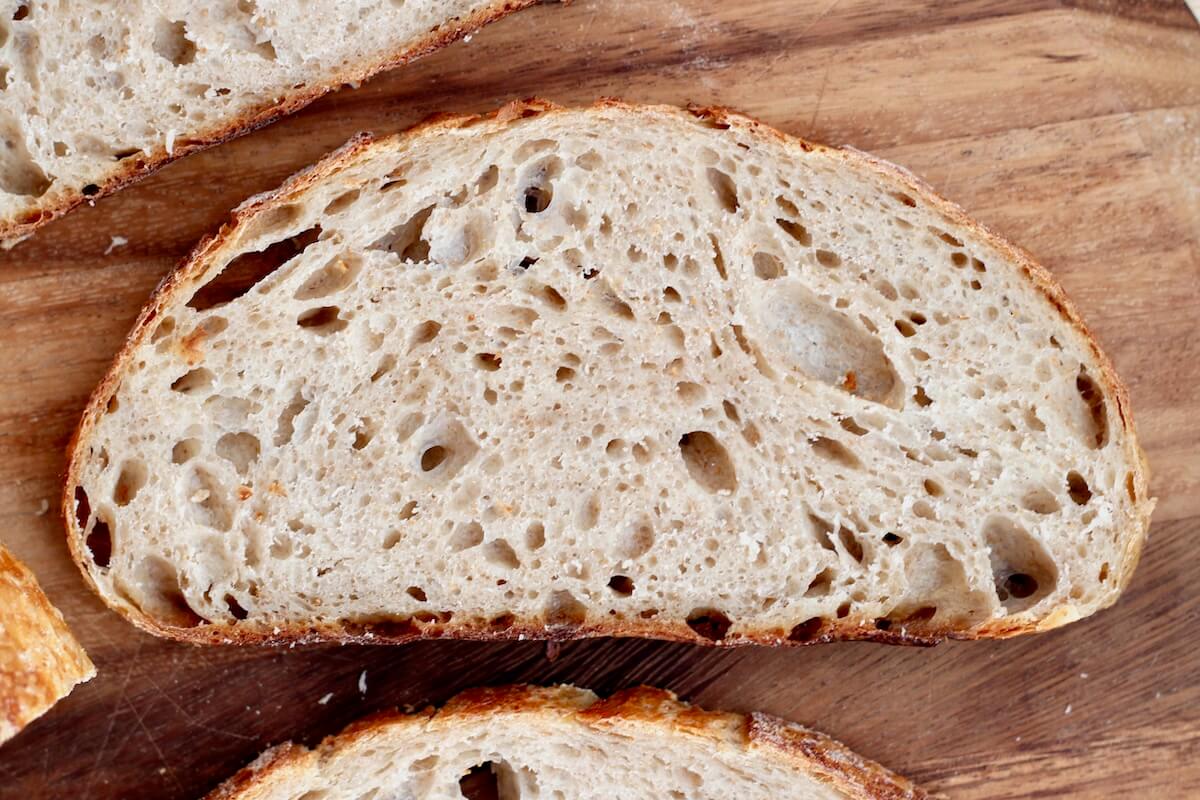 Slices of same day sourdough bread on a wooden cutting board.