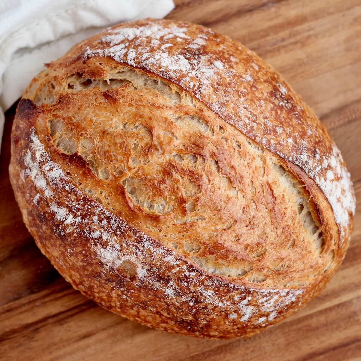 A whole loaf of same day sourdough bread on a wooden cutting board.