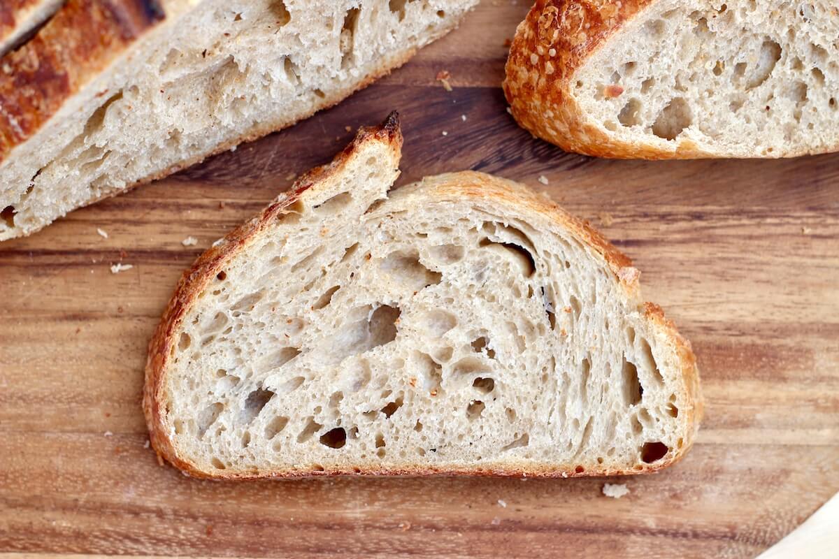 A slice of sourdough beer bread on a wooden cutting board.