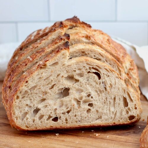 A sliced loaf of beer sourdough bread on a wooden cutting board.